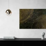 Energetic abstract landscape with black, gold and dark greenposter format displayed in a grey wall, black desk