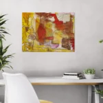 Warm conceptual abstract landscape with mustard yellow, red and brownposter format displayed in a white desk with decorative plants