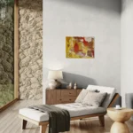 Warm conceptual abstract landscape with mustard yellow, red and brownposter format displayed in a living space with glass walls, reclined couch, accent rock wall