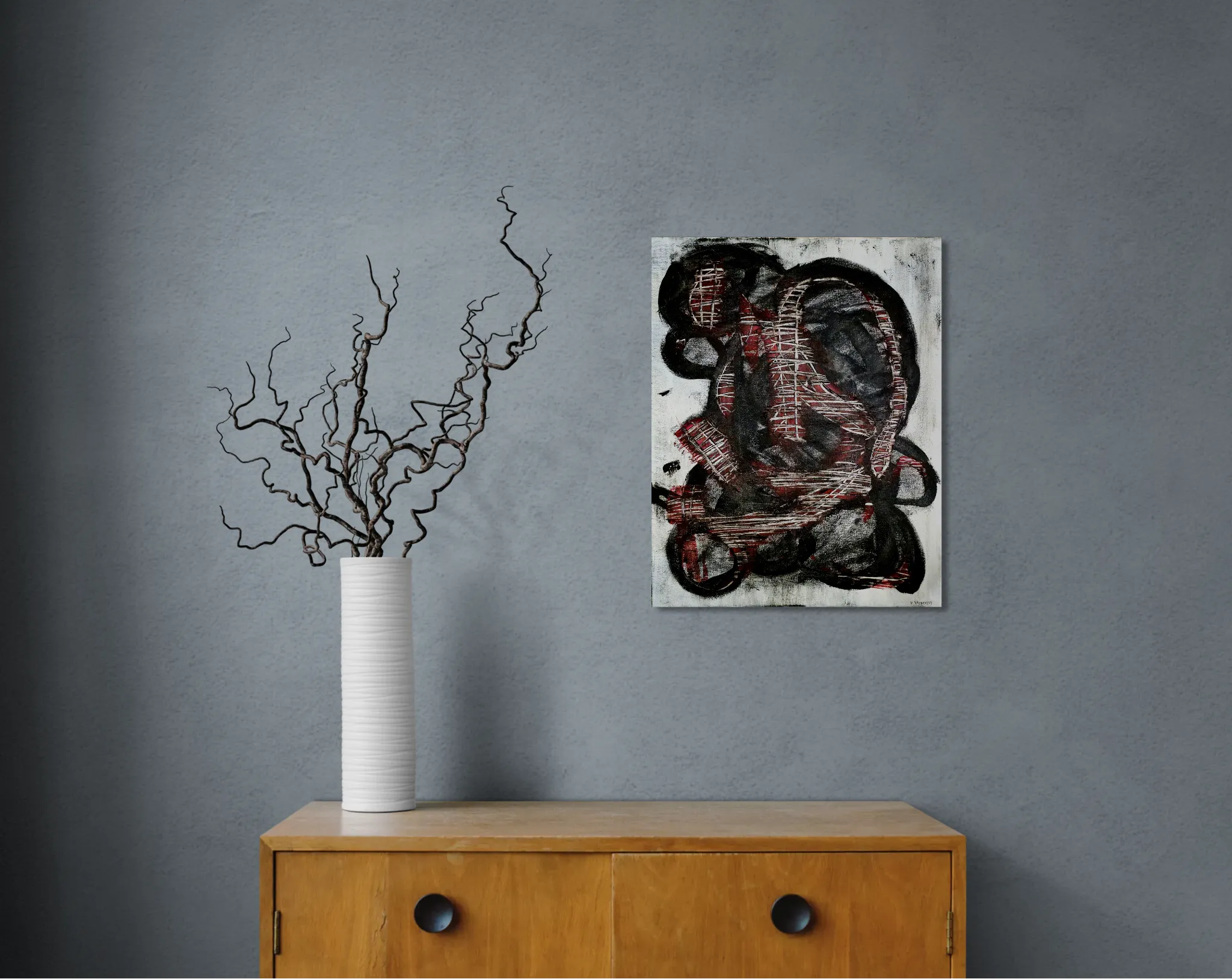 Dark and conceptual abstract portrait in white, black and redoriginal format displayed in a grey wall with wooden cabinet and vase with curly twicks