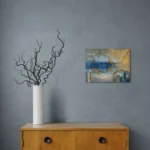 Dreamy glowing abstract landscape in blue and goldoriginal format displayed in a grey wall with wooden cabinet and vase with curly twicks