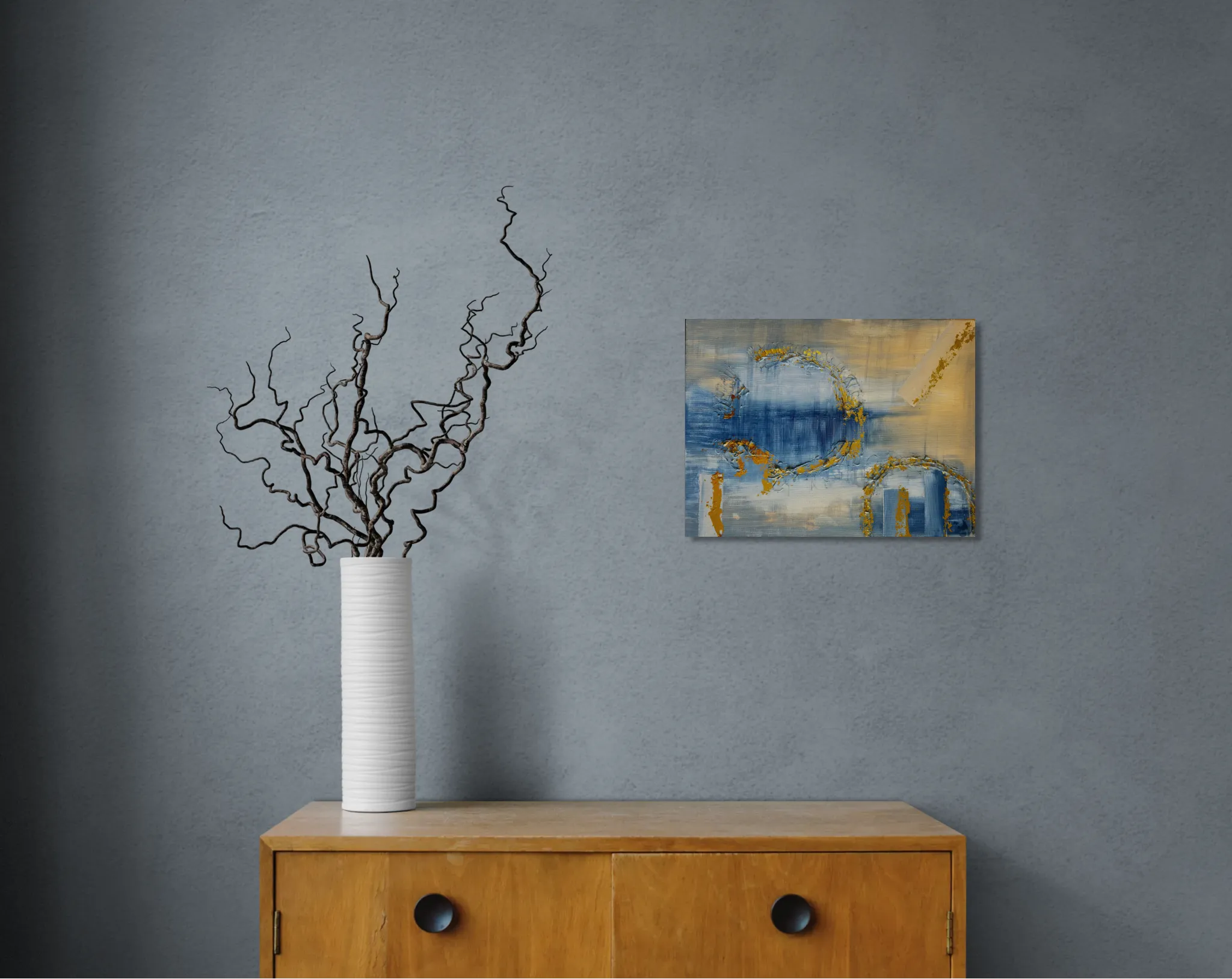 Dreamy glowing abstract landscape in blue and goldoriginal format displayed in a grey wall with wooden cabinet and vase with curly twicks