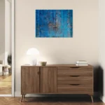 Layered and glowing abstract landscape in orange and blueposter format displayed in a corredor with wooden furniture