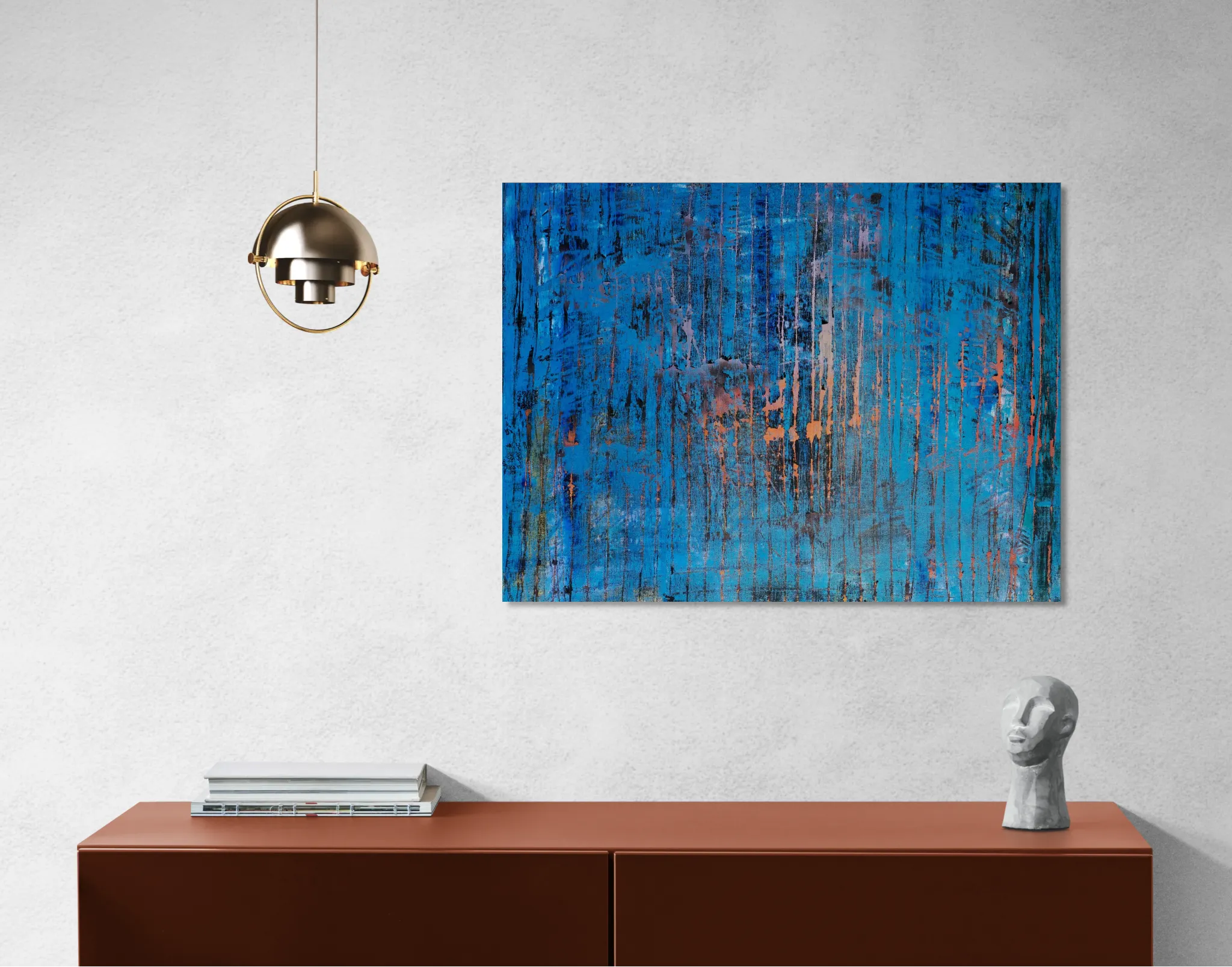Layered and glowing abstract landscape in orange and blueposter format displayed in a grey wall, brown desk