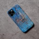 Phone case displayed on a grey concrete surface featuring the artwork “AZUL”, a blue and orange layered expressive abstract piece.