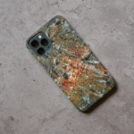 Phone case displayed on a grey concrete surface featuring the artwork “Caracas”, a planet-like textured orange and grey abstract artwork.