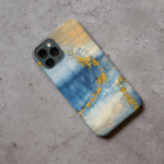 Phone case displayed on a grey concrete surface featuring the artwork “Venice”, a blue and gold abstract painting.