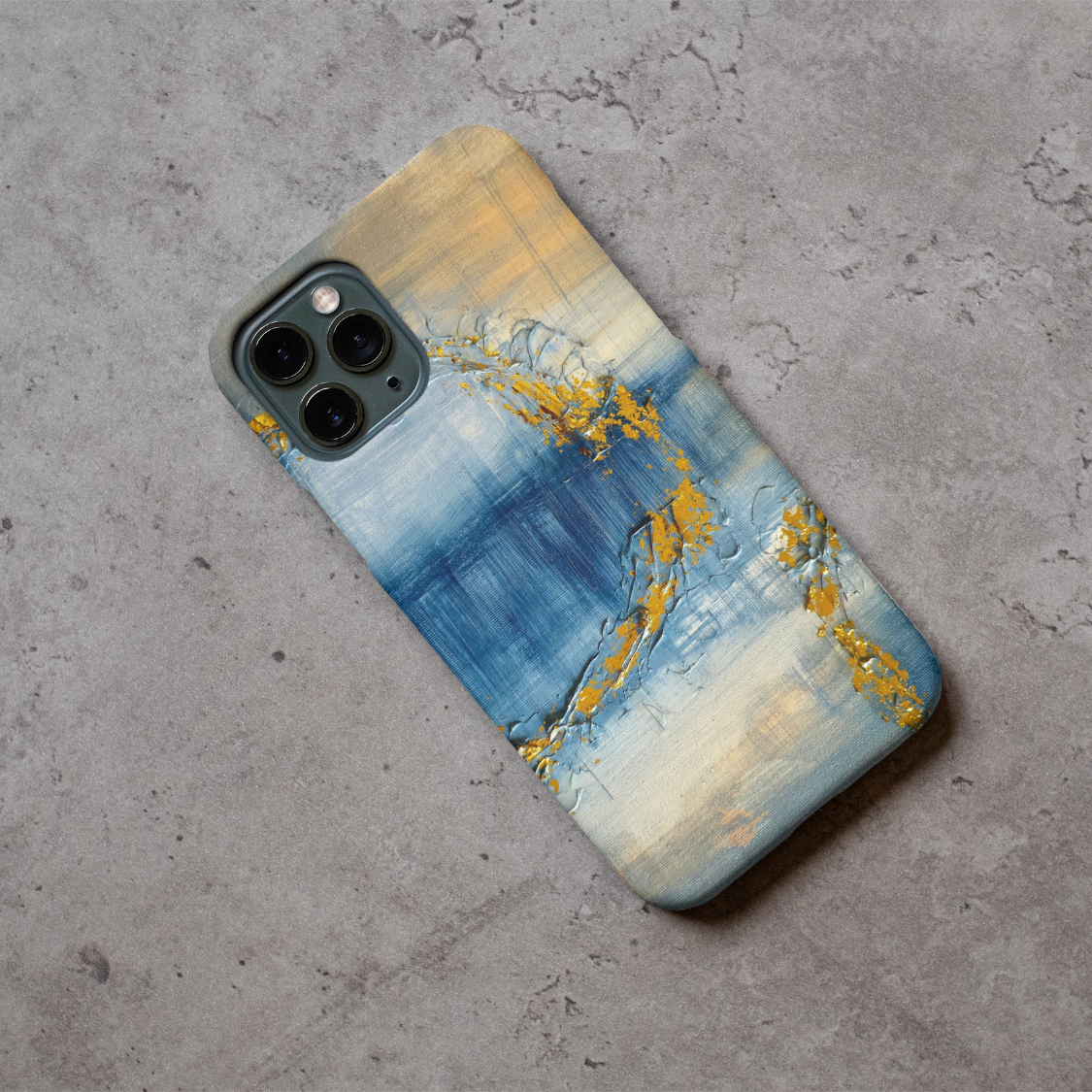 Phone case displayed on a grey concrete surface featuring the artwork “Venice”, a blue and gold abstract painting.