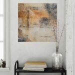 Abstract art poster with sunset warmth, adding bold contrast for modern interior. On grey wall behind trolley with flowers and books