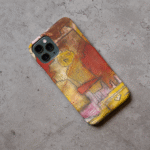Phone case displayed on a grey concrete surface featuring the artwork “Cairo”, a yellow and red abstract piece with ancient figures.
